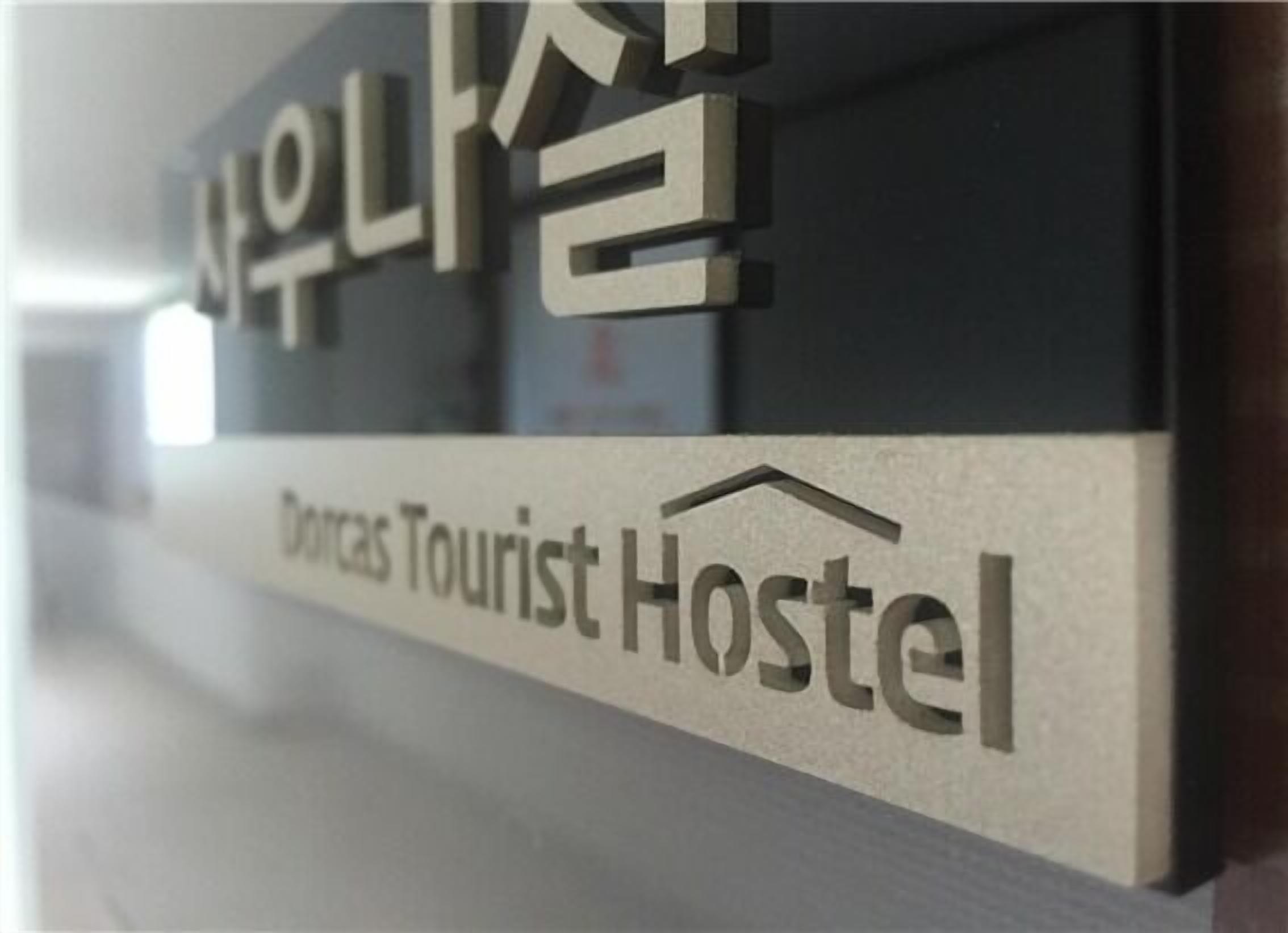 A sign for Dorcas Tourist Hostel with a modern design.