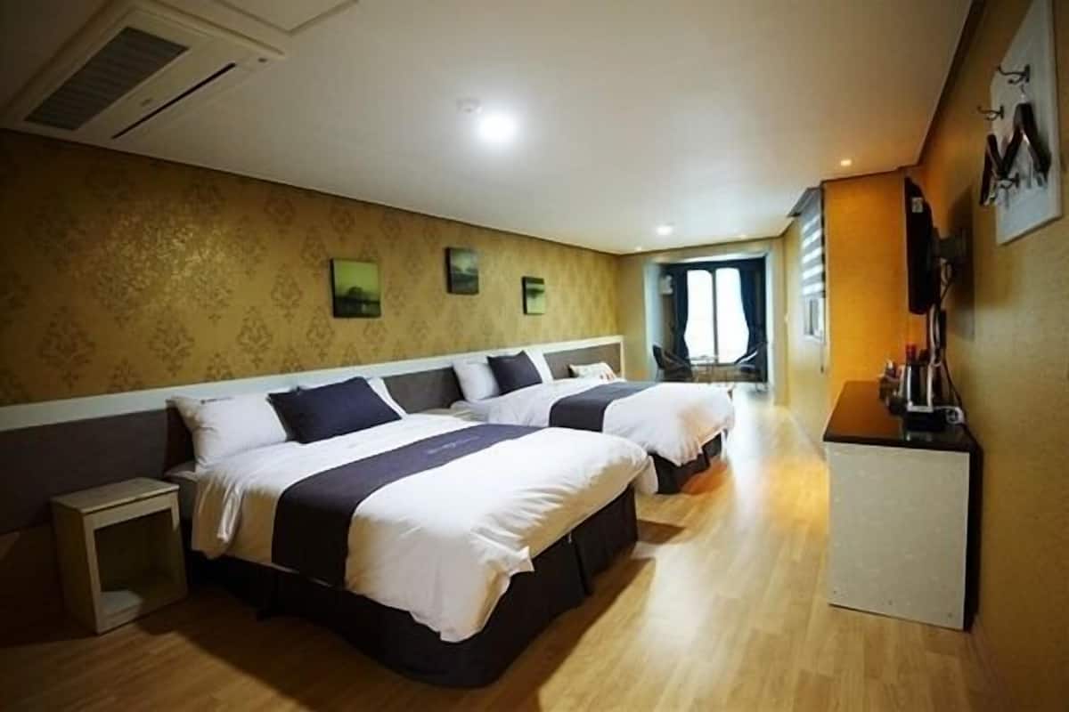 Een hotelkamer met twee bedden, een klein bureau en een televisie.