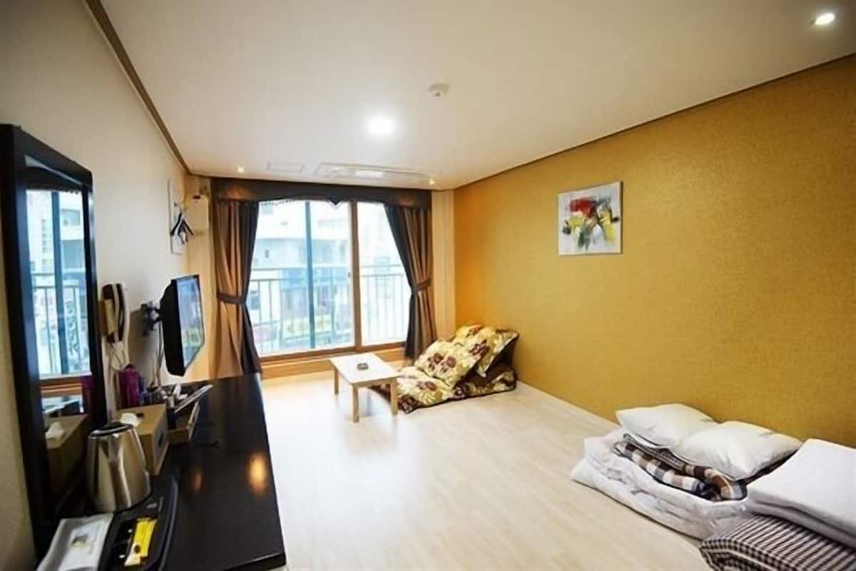 Een hotelkamer met een bed, een klein tafeltje, een televisie en een raam met gordijnen.