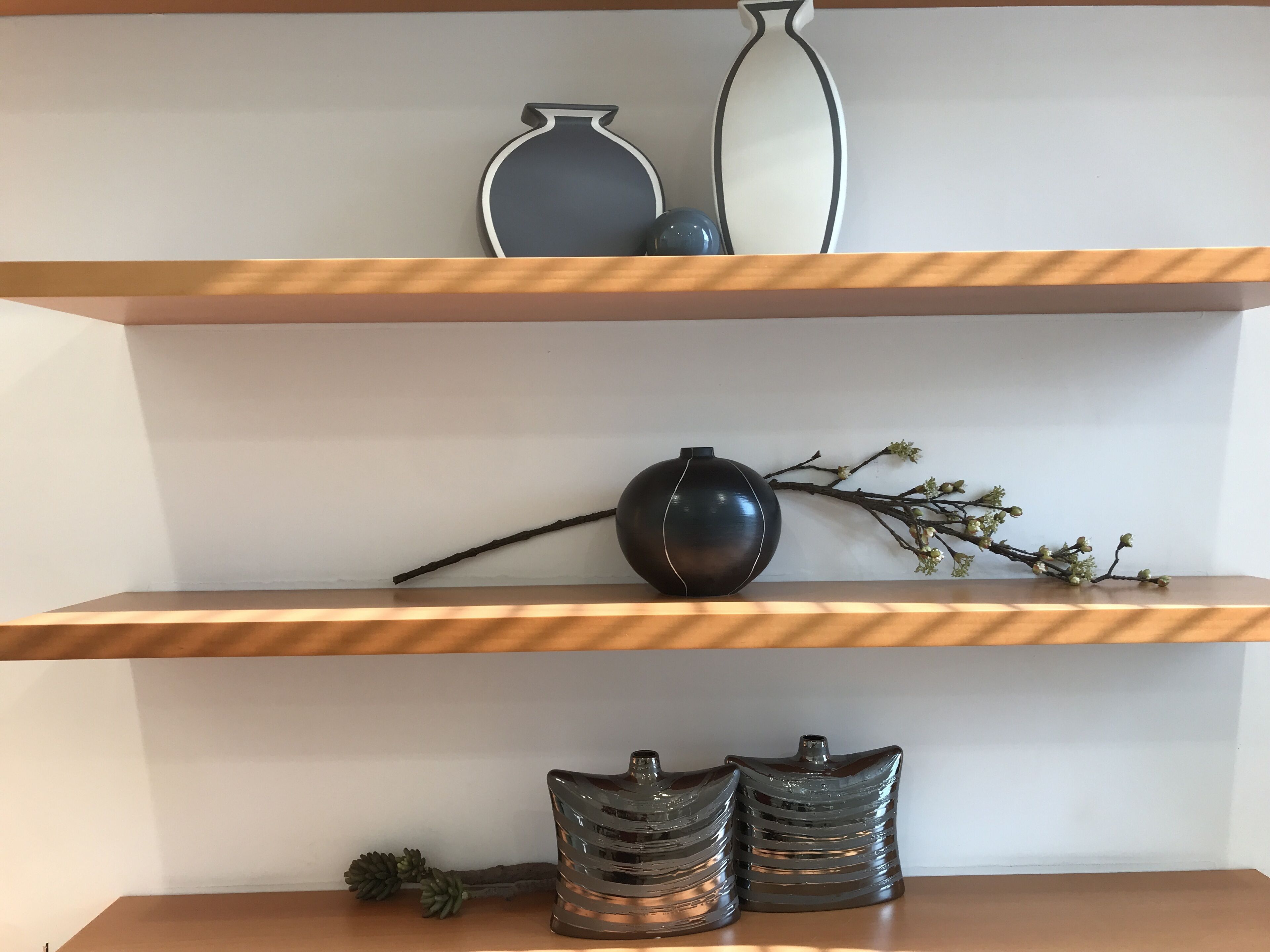 Una estantería con jarrones decorativos y ramas.