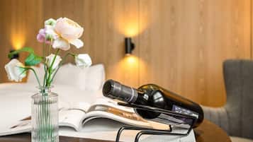 A wooden wall with a vase of flowers and a wine bottle on a table.