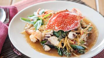 Une assiette de fruits de mer, surmontée d’un crabe, servie dans une assiette blanche avec une serviette rouge placée en dessous.