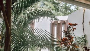 Un área de spa con un jacuzzi rodeado de exuberante follaje tropical y una pérgola de madera.