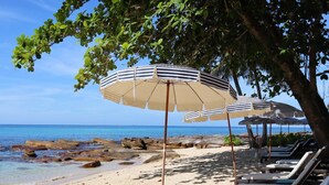 Una playa con sillas de descanso y sombrillas a rayas.