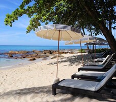 On the beach, white sand, sun loungers, beach umbrellas