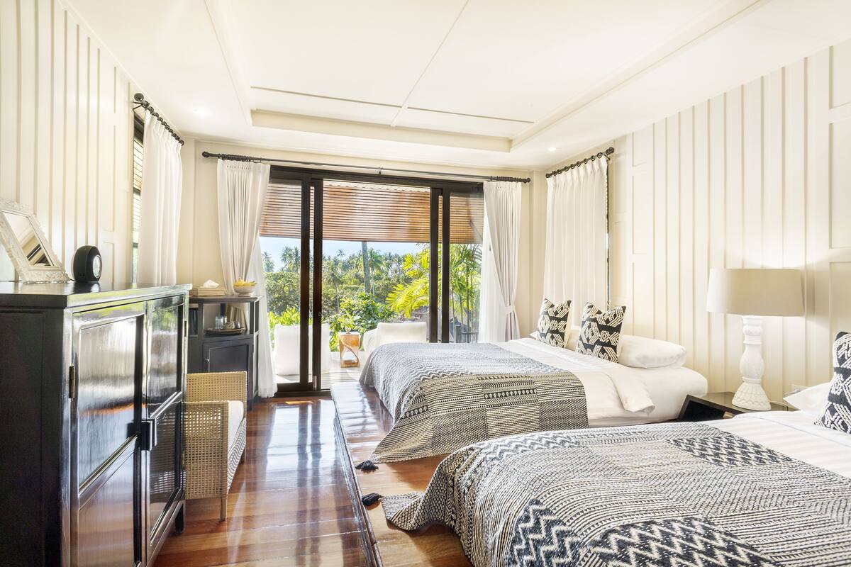Habitación de hotel con dos camas, un escritorio y vistas al exterior.