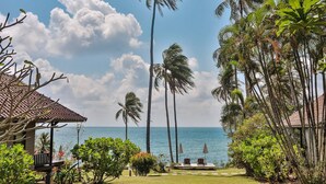 A beach view with palm trees, a gazebo, and a lounge area with umbrellas.