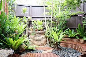 A garden with various plants, a brick planter, and a curved brick pathway. - Shantaa Resort (Ko Kood)