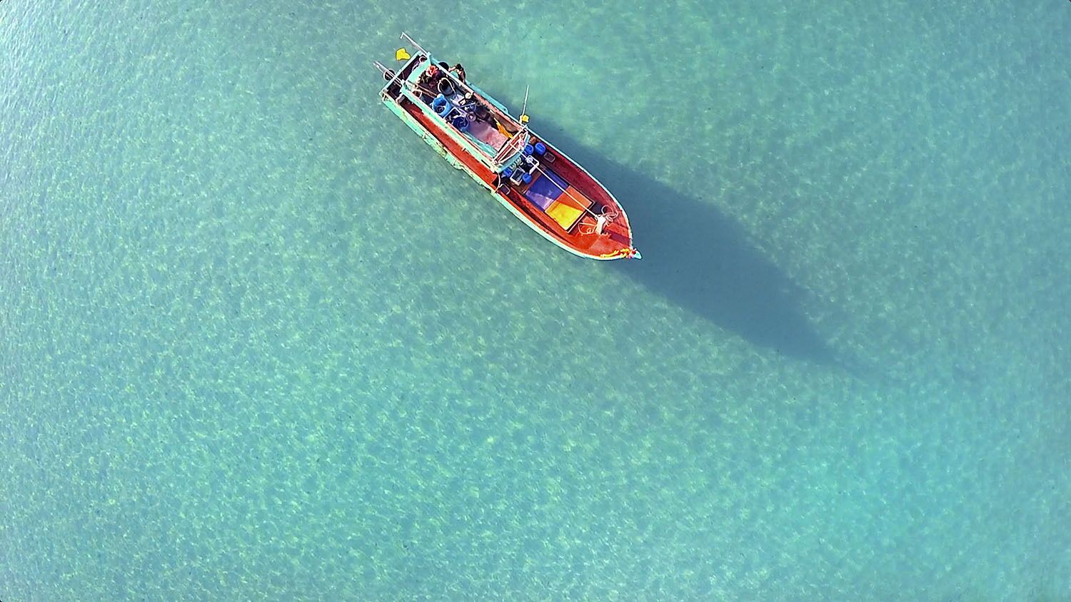 An aerial view of a boat on clear turquoise water.