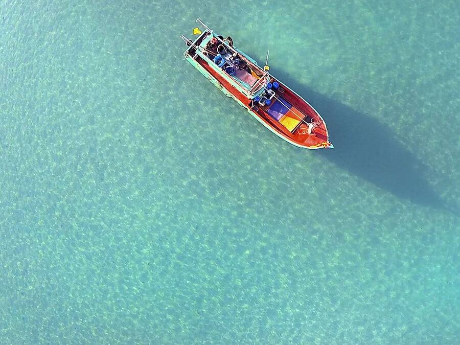An aerial view of a boat on clear turquoise water.
