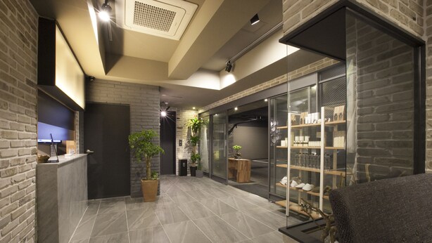 Un interior moderno con una recepción, plantas en macetas y una vitrina de vidrio.