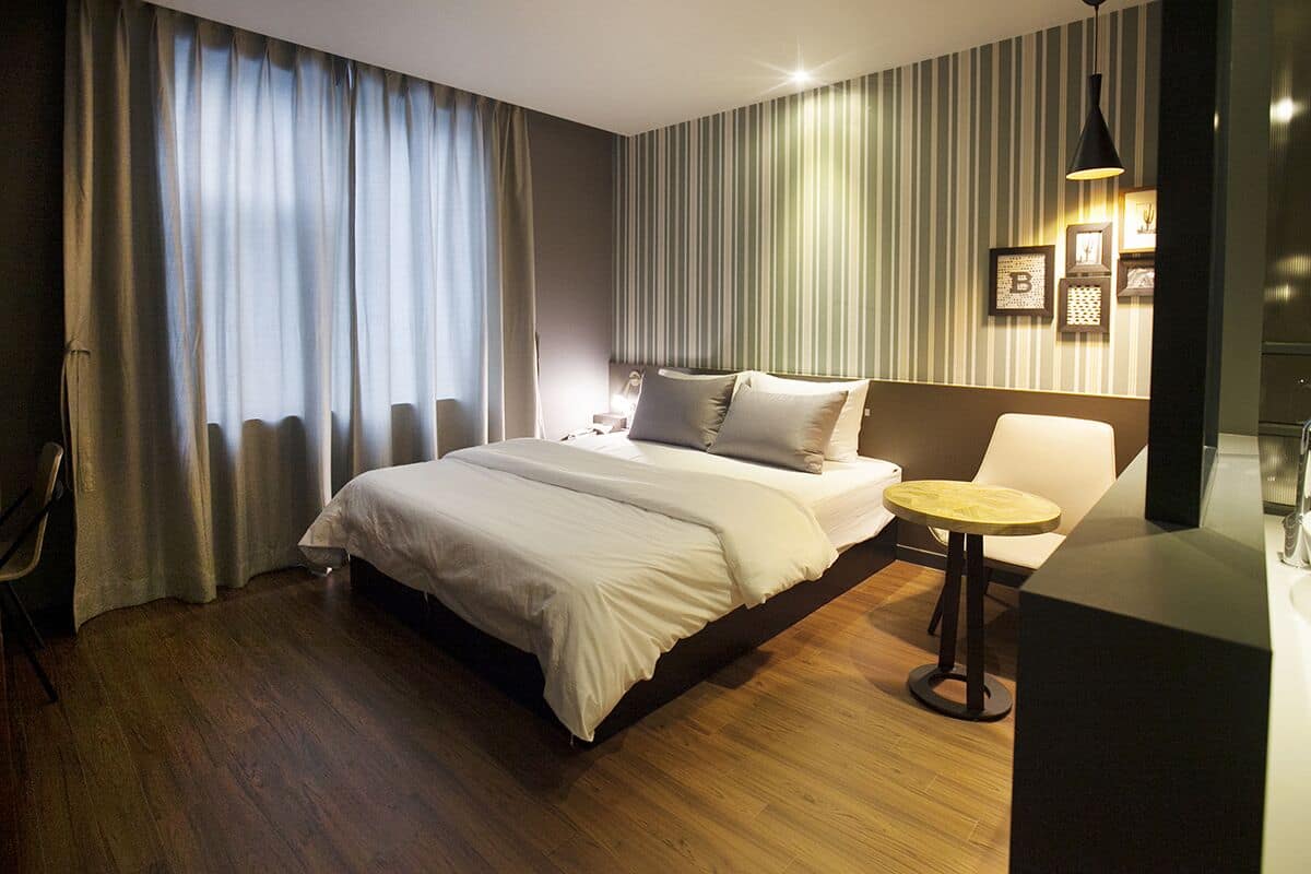Una habitación de hotel moderna con una cama grande, una mesita de noche, una silla y una pequeña mesa redonda.