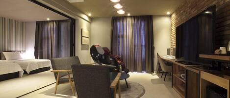 A modern hotel room with a bed, a desk, a chair, and a TV.