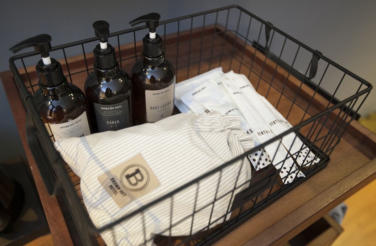 A black wire basket containing toiletries, a striped towel, and a set of dice.