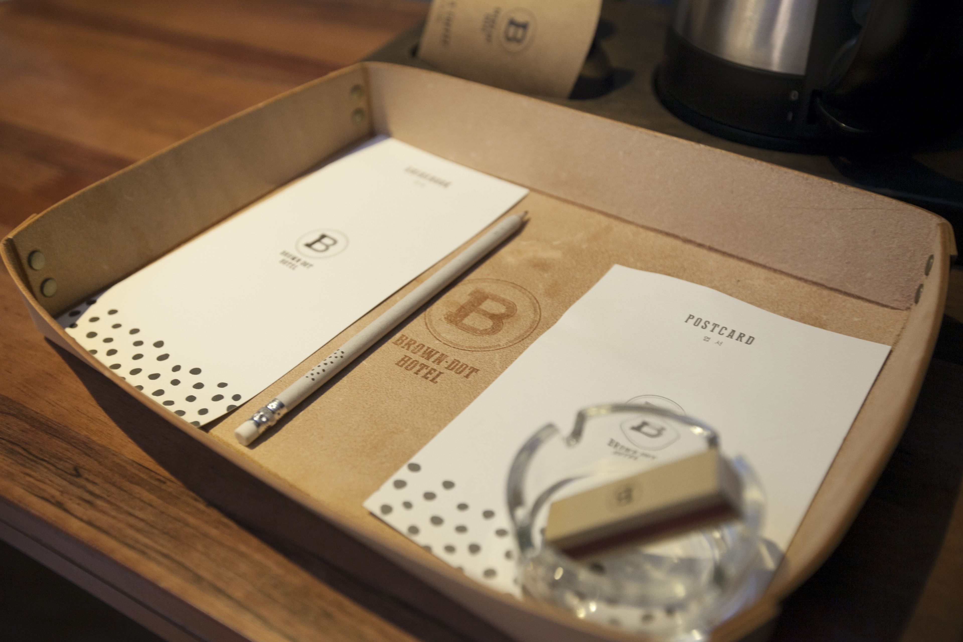 Una caja que contiene un pasaporte, un bolígrafo y una tarjeta con la inscripción "BROWN DOT HOTEL".