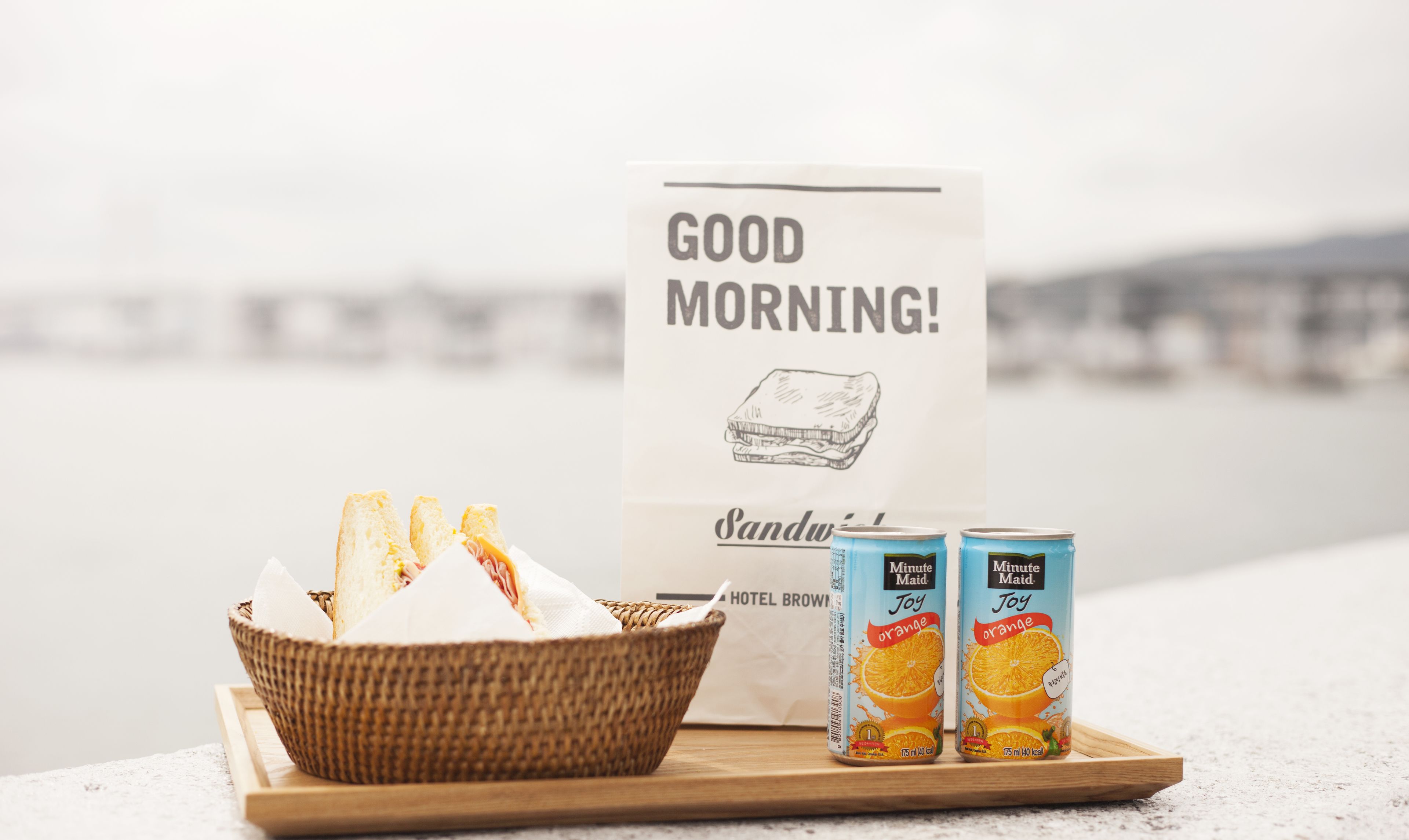 A breakfast tray with bread, a sandwich, and Minute Maid orange juice cans.