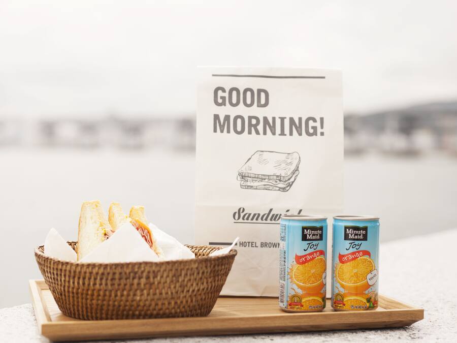 A breakfast tray with bread, a sandwich, and Minute Maid orange juice cans.