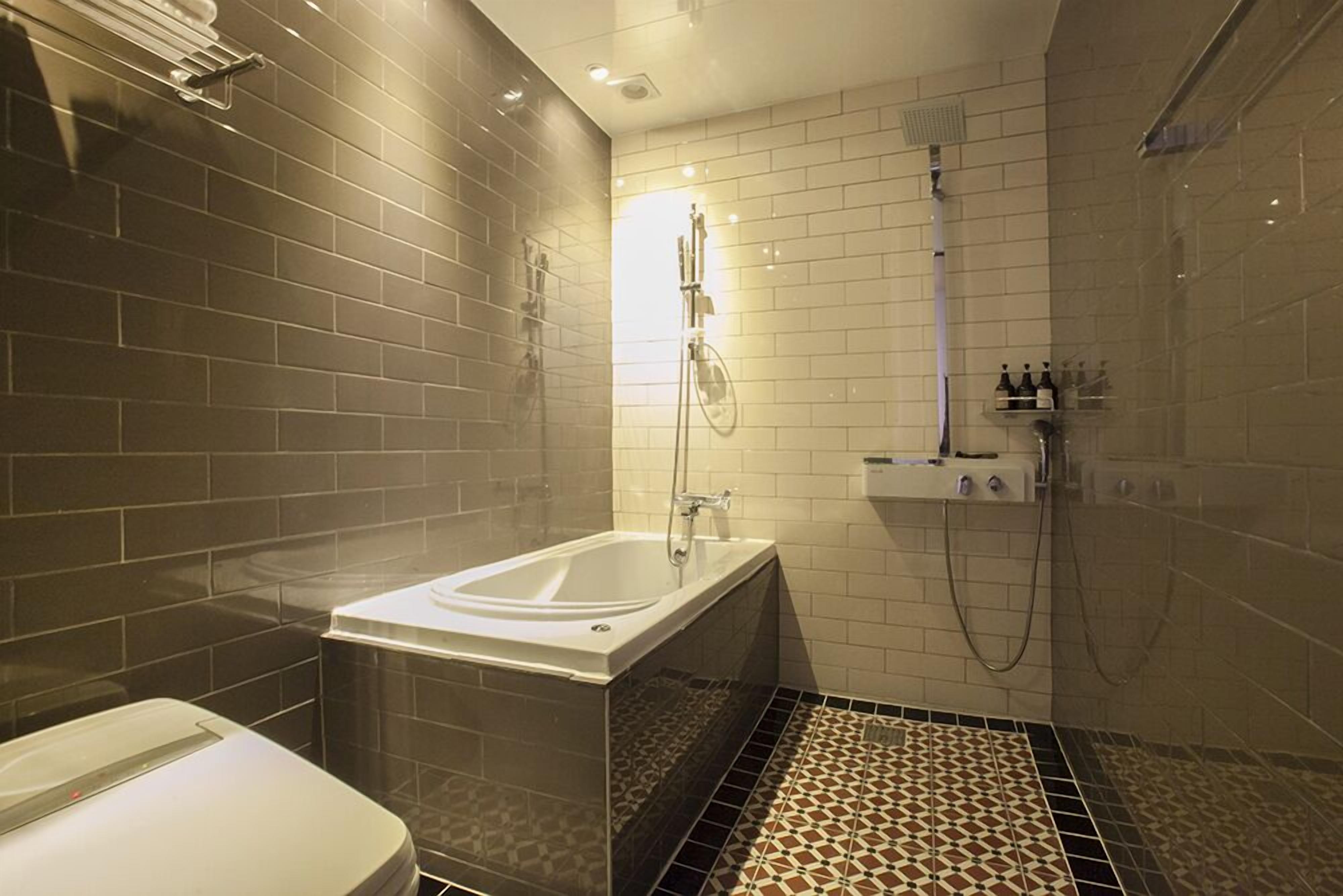 Een moderne badkamer met een bad, douche en toilet.
