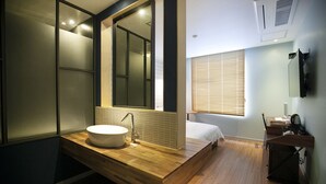 Un baño moderno con tocador de madera, un espejo grande y lavamanos integrado.