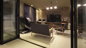 Una sala de estar moderna con una caminadora, un televisor de pantalla plana grande y una pared de ladrillo.