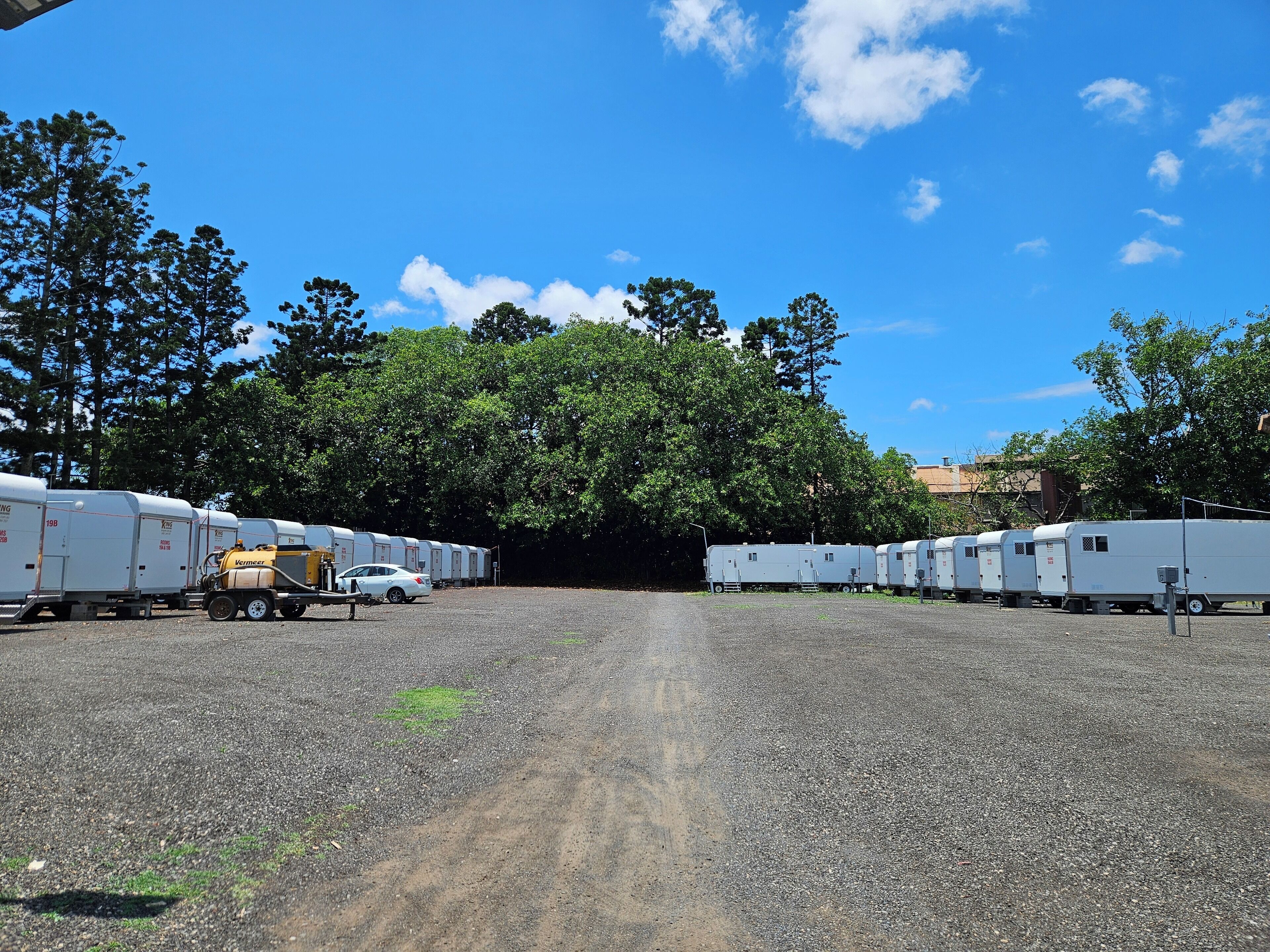 A gravel parking area with several RVs and a truck.
