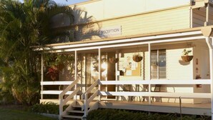 A reception area with a staircase leading to the entrance, a reception desk, and a sign indicating 'RECEPTION'. - AAOK Riverdale Caravan Park (Bundaberg North)