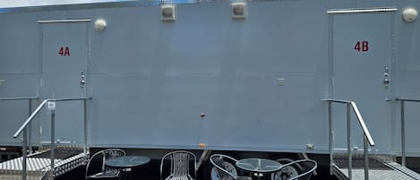 A portable restroom with metal railings and a small table with chairs.