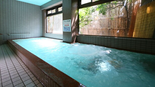 A hot tub area with tiled walls, a window with a view of greenery, and a sign with text. - Fukashiso (Matsumoto)