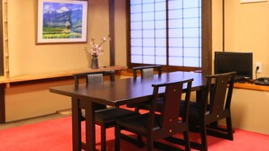 A traditional Japanese-style room with tatami flooring, a low table, and wooden chairs. - Fukashiso (Matsumoto)