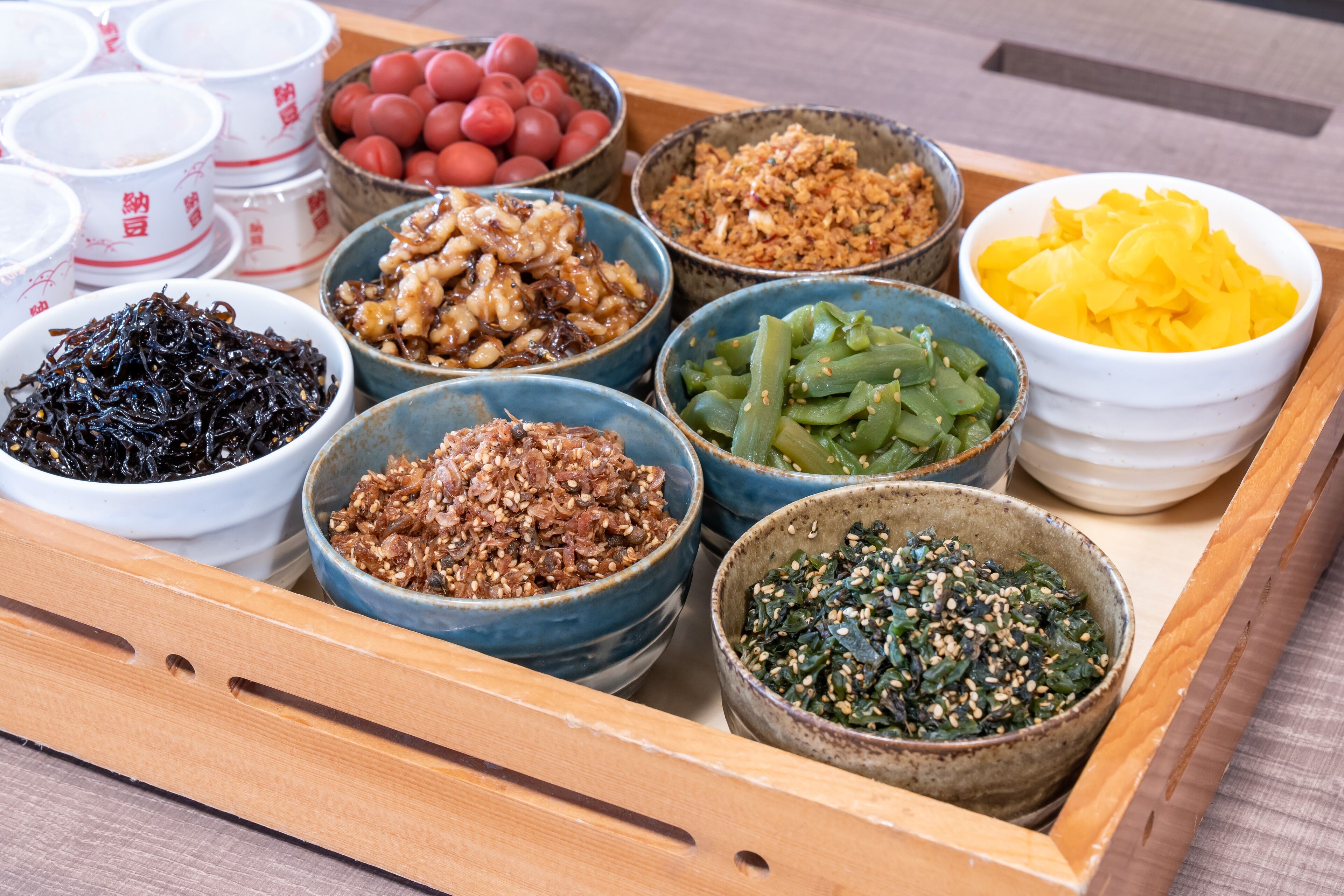 A wooden tray with various bowls of food, including seaweed, kimchi, and vegetables.