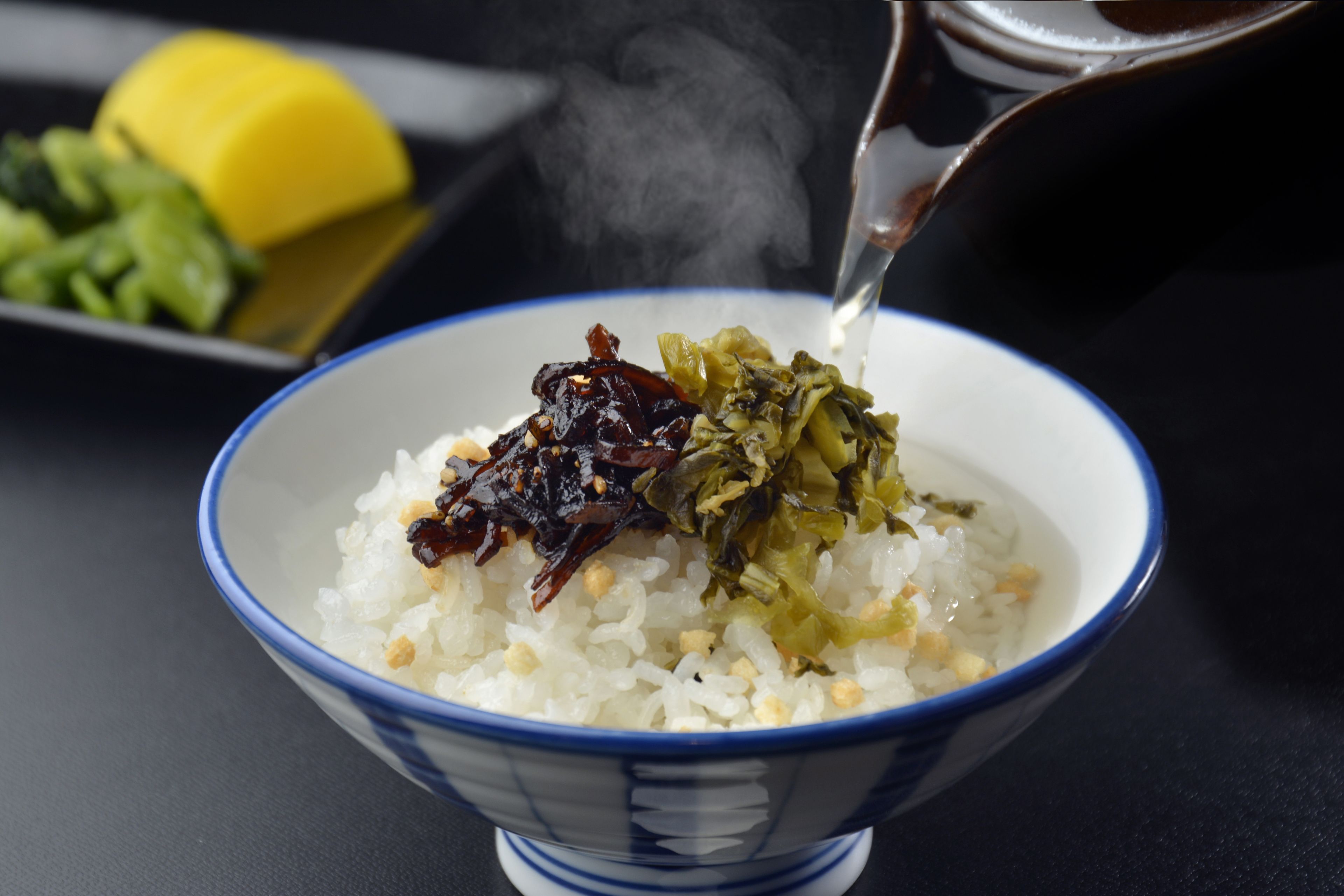 Un tazón de arroz con alga y pescado seco que se sirve desde una olla.