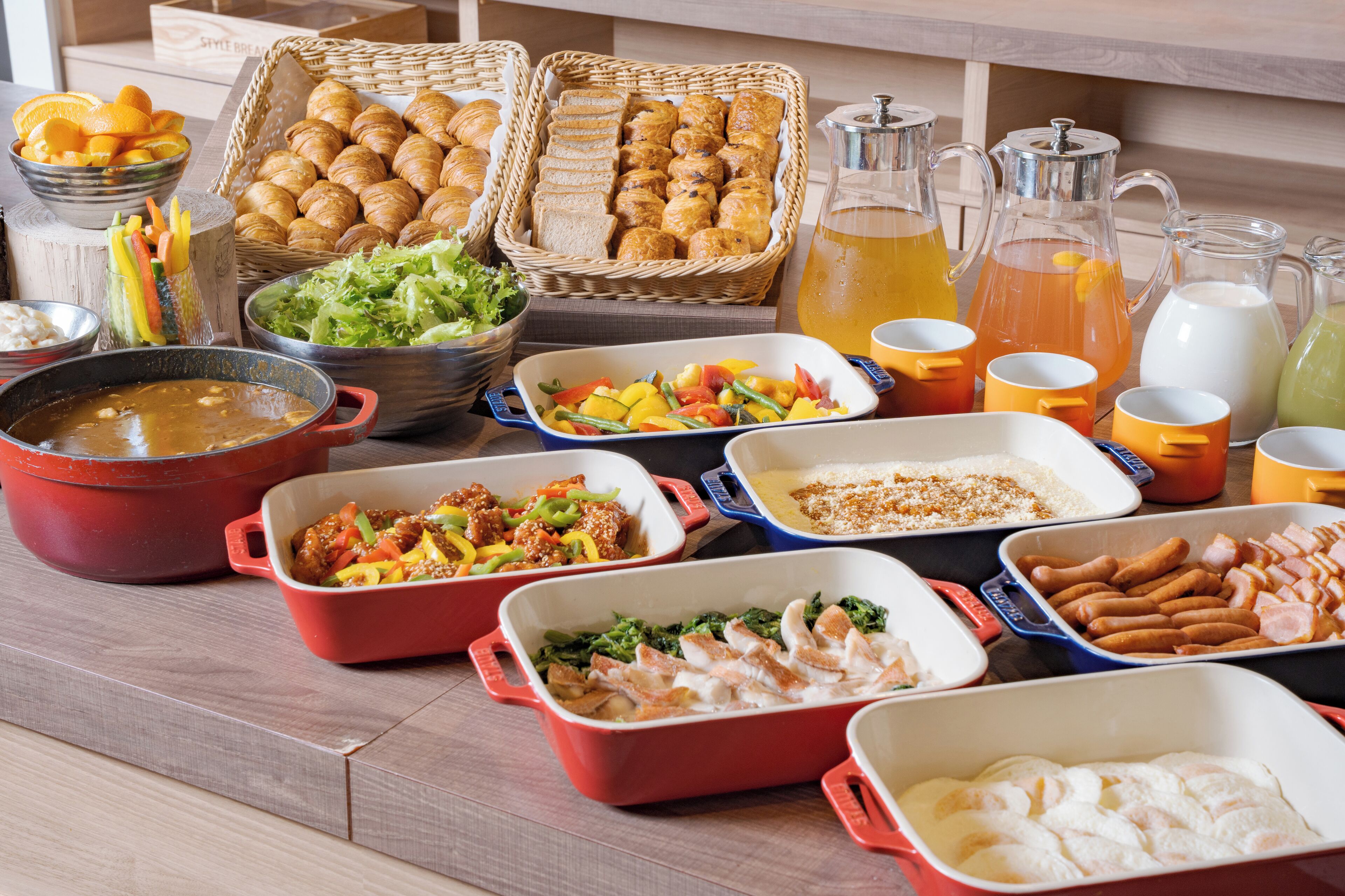 Una mesa de buffet con diversos platos, entre ellos ensaladas, carnes y pasteles.