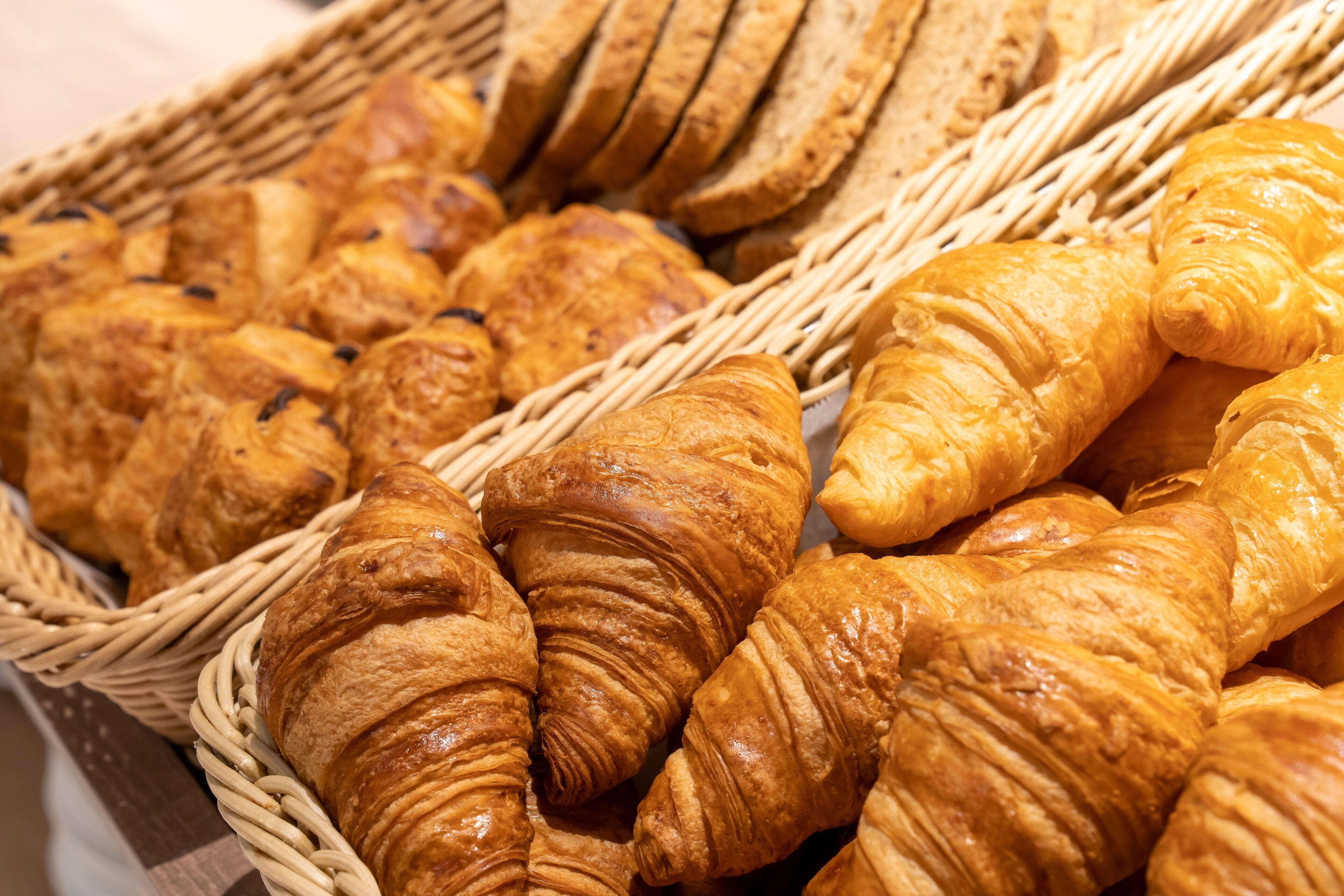 Una cesta llena de diferentes tipos de pan, como croissants y barras.