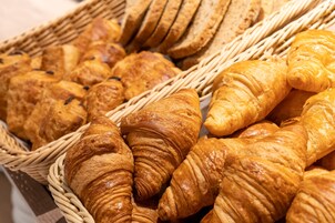 Una cesta llena de diferentes tipos de pan, como croissants y barras.