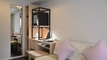 Ein gemütliches Schlafzimmer mit Bett, Schreibtisch mit Computer, Spiegel und Kleiderschrank.