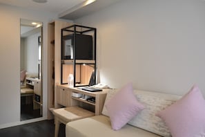 Un dormitorio pequeño con cama, escritorio con computadora, espejo y armario.