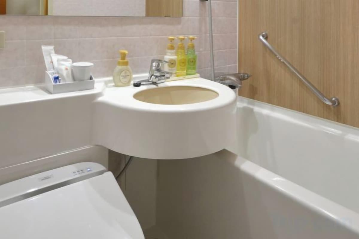 A bathroom with a sink, mirror, and handrail.