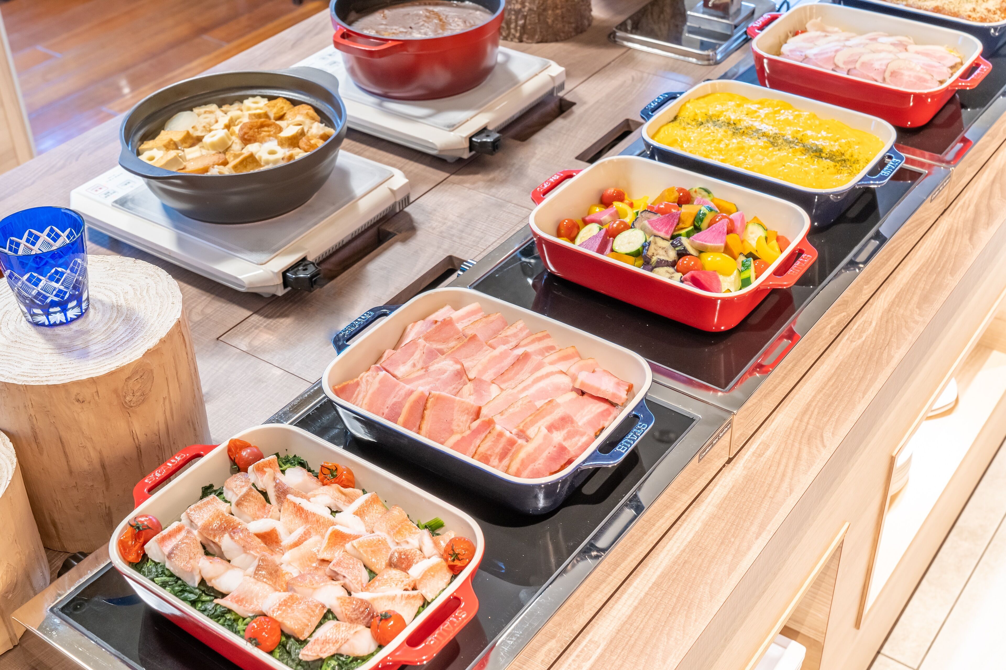 Un bufé con diversos platos, incluyendo carnes, verduras y un bol de gofres.