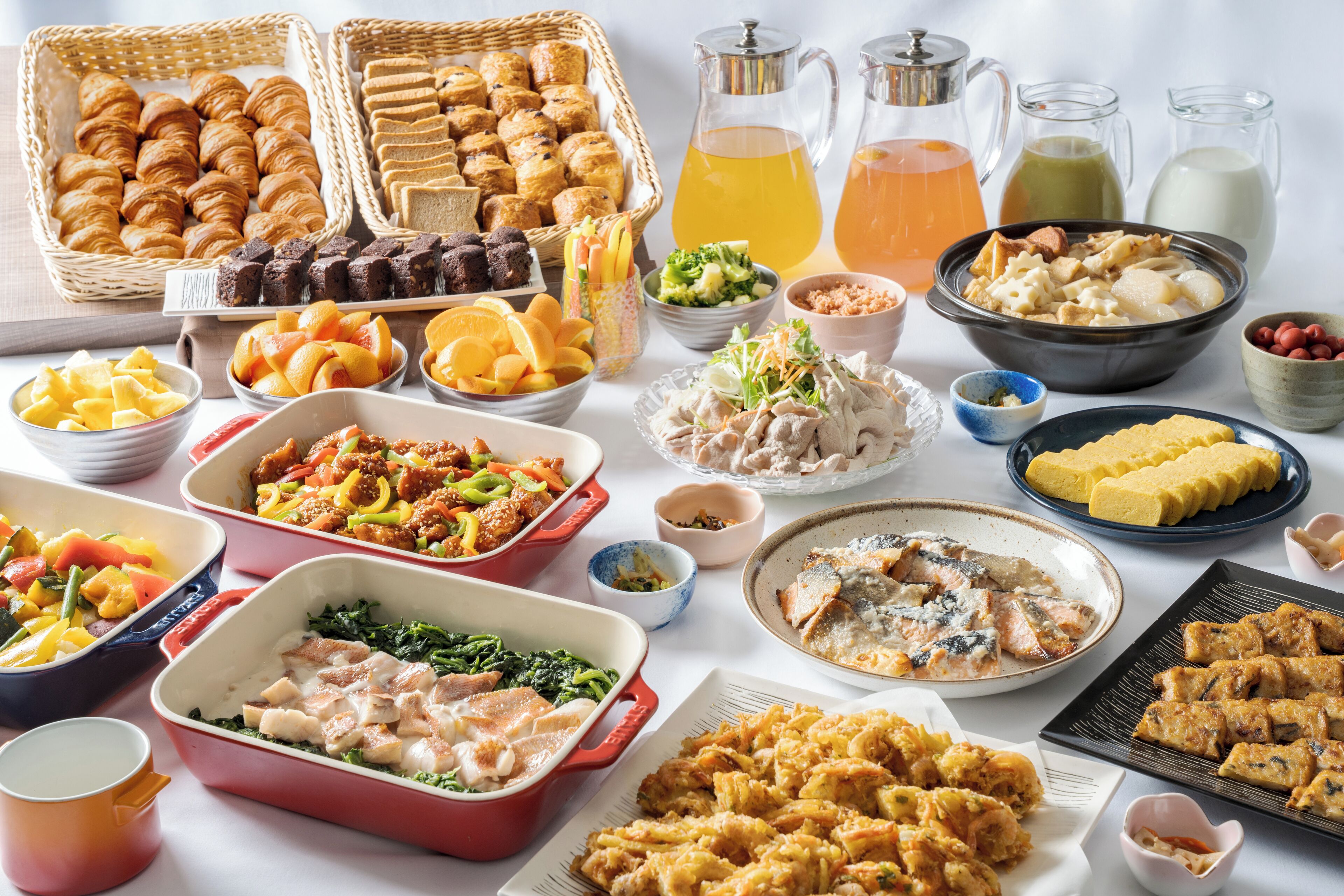 A variety of food items including pastries, fruits, and dishes in different serving dishes.
