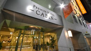 Het uiterlijk van Hotel Premier Cabin, met een draaiende glazen deur en een bord met de naam.