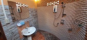 A bathroom with a stone wall design, a sink, and a shower. - Macura Resort (Ko Chang)