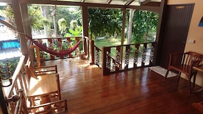 A wooden deck with a hammock, chairs, and a view of a lush garden. - Macura Resort (Ko Chang)