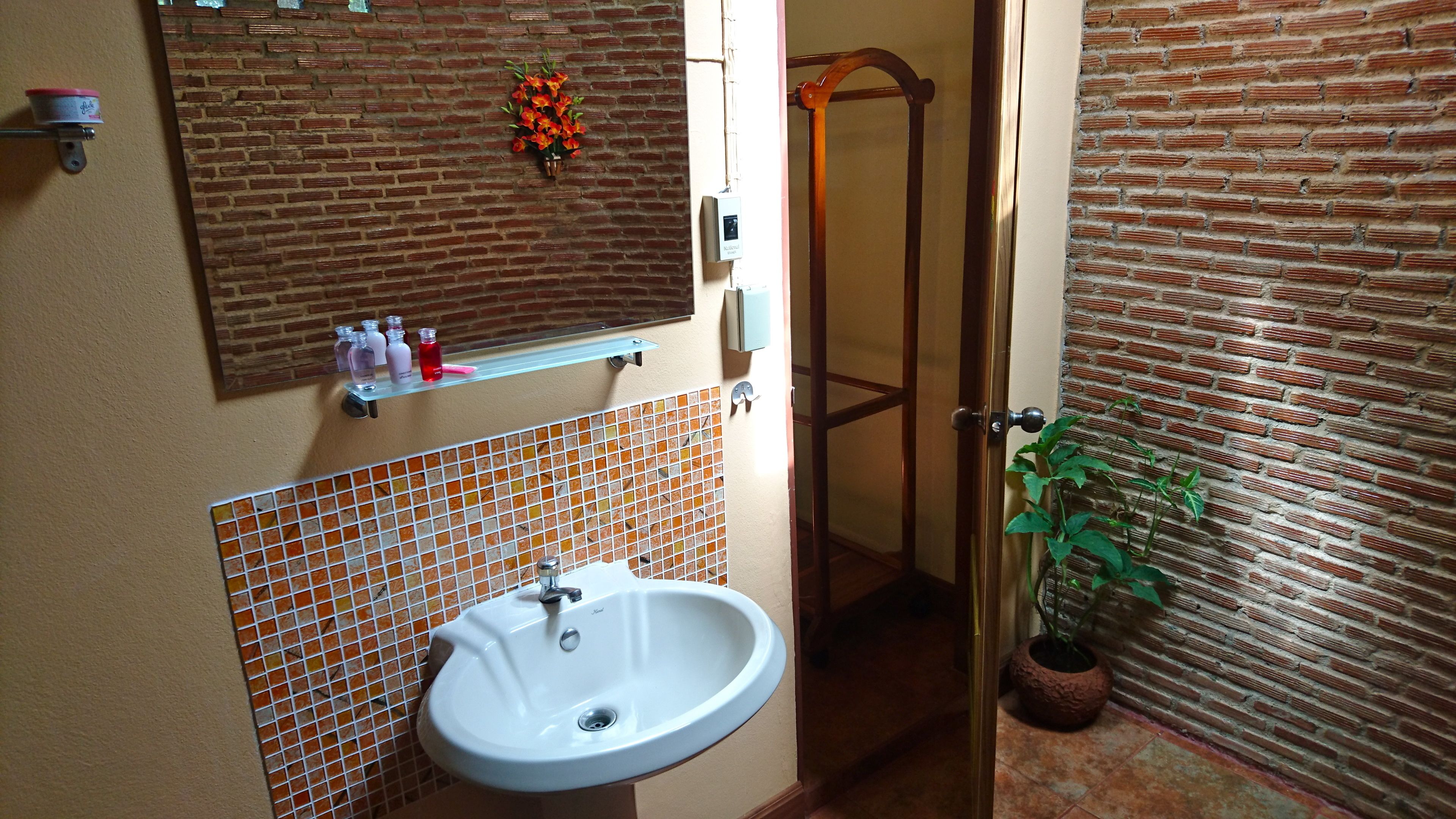 Een badkamer met een witte wastafel, een spiegel en een douche.