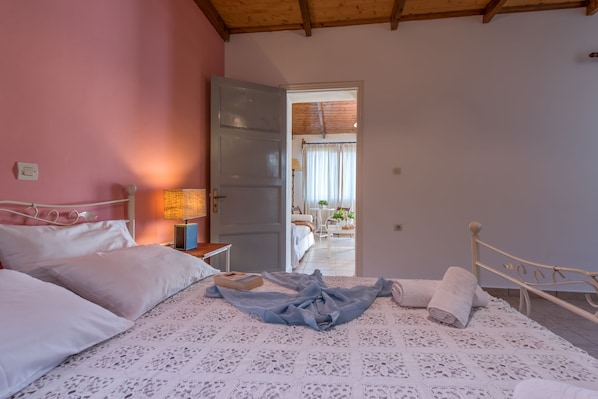 A bedroom with a bed, a nightstand, and a door leading to a balcony. - Lofos Soilis (Zakynthos)