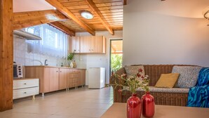 A kitchen with wooden cabinets, a white refrigerator, and a dining table with red vases. - Lofos Soilis (Zakynthos)