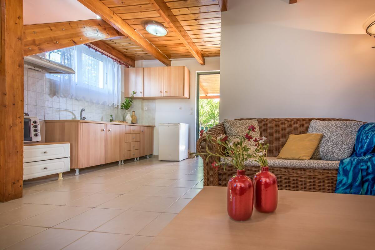 A kitchen with wooden cabinets, a white refrigerator, and a dining table with red vases.