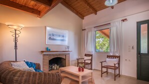 A cozy living room with a fireplace, wicker furniture, and a view of the outdoors. - Lofos Soilis (Zakynthos)