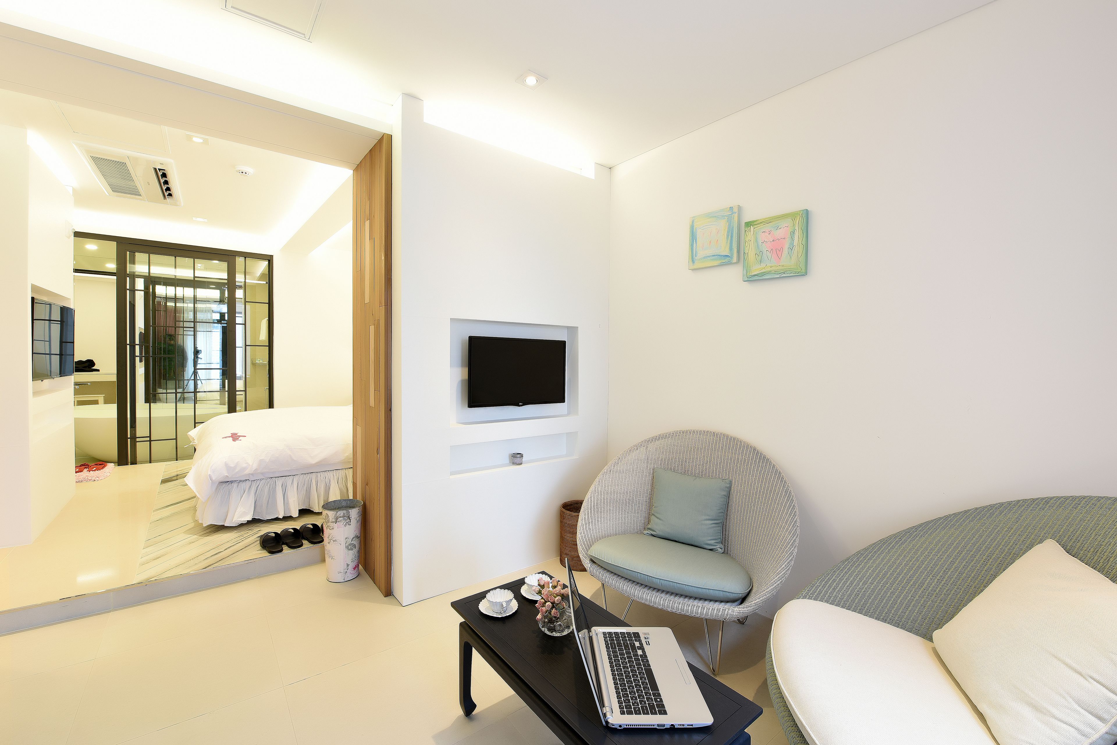 Een moderne hotelkamer met een bed, een laptop op een tafel, een televisie en een stoel.