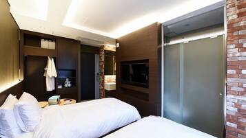 A hotel room with two beds, a wardrobe, a TV, and a small table with a cup and a book.