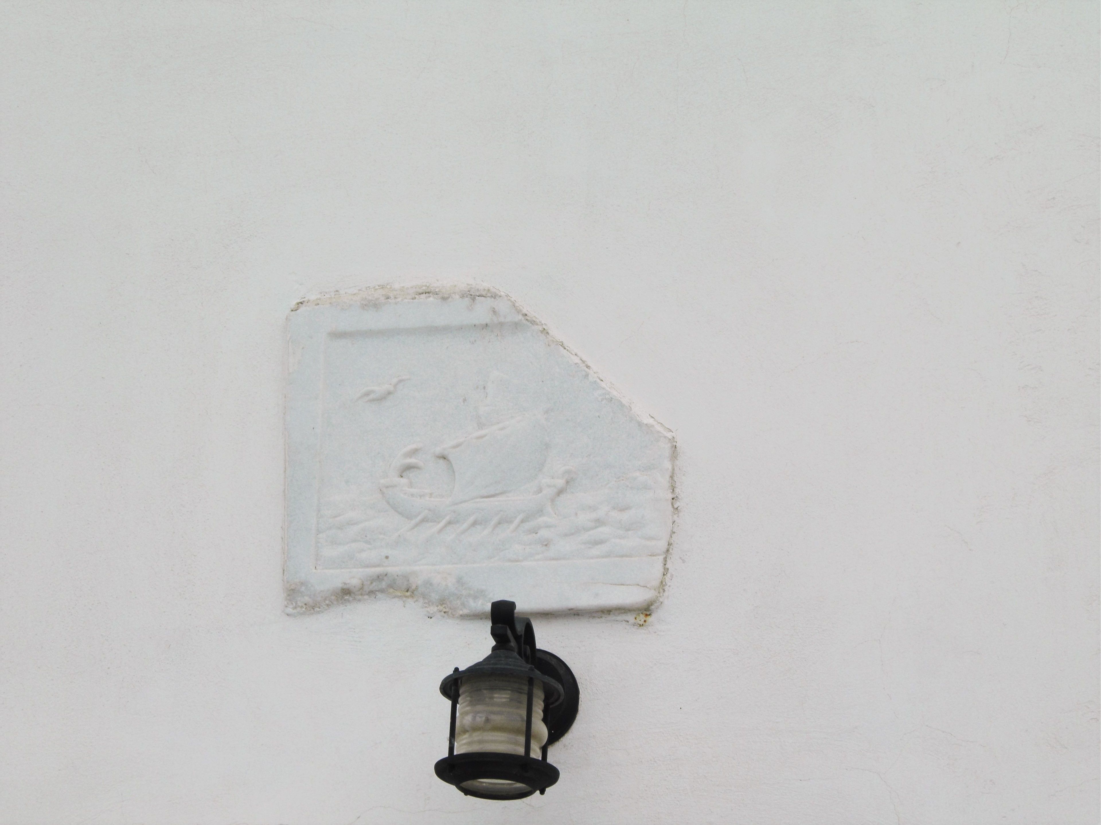 A wall-mounted light fixture with a decorative relief of a boat and waves.